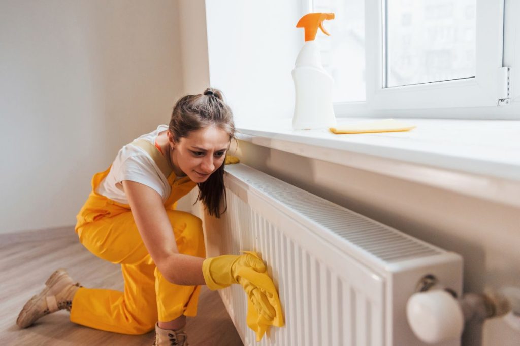 maid cleaning a baseboard radiator
